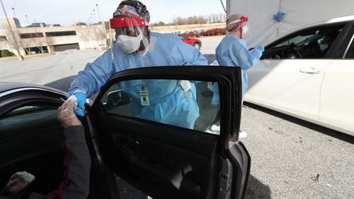 Registered nurses Katrina McCord (left) and Elham Roshanraun (right) work a line of motorists at a free drive-thru COVID-19 DeKalb Board of Health testing site located by the BrandsMart USA while coronavirus testing surges. (Curtis Compton / Curtis.Compton@ajc.com)