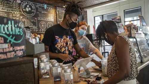 Urban Grind coffeeshop employees Byron Reid, left, and Hollyn Richards, second from left, wear masks as they help a customer purchase a beverage at the coffee shop in Atlanta. (Alyssa Pointer/Atlanta Journal Constitution)