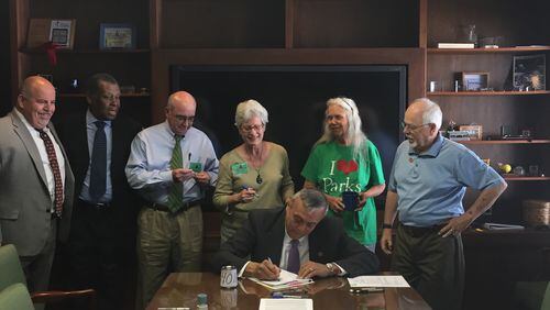 Cobb Commission Chairman Mike Boyce signs a document to execute Cobb County’s 2017 Series Parks Bond while other county officials and members of Cobb Parks Coalition look on. Courtesy of Cobb County