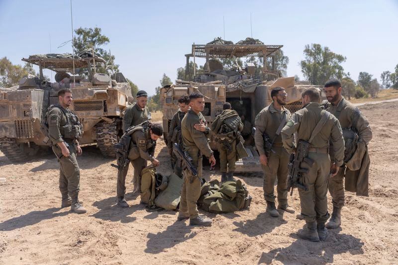 Israeli soldiers stand next to personnel carriers (APC) near the Israeli-Gaza border, in southern Israel, Monday, April 15, 2024. (AP Photo/Ohad Zwigenberg)