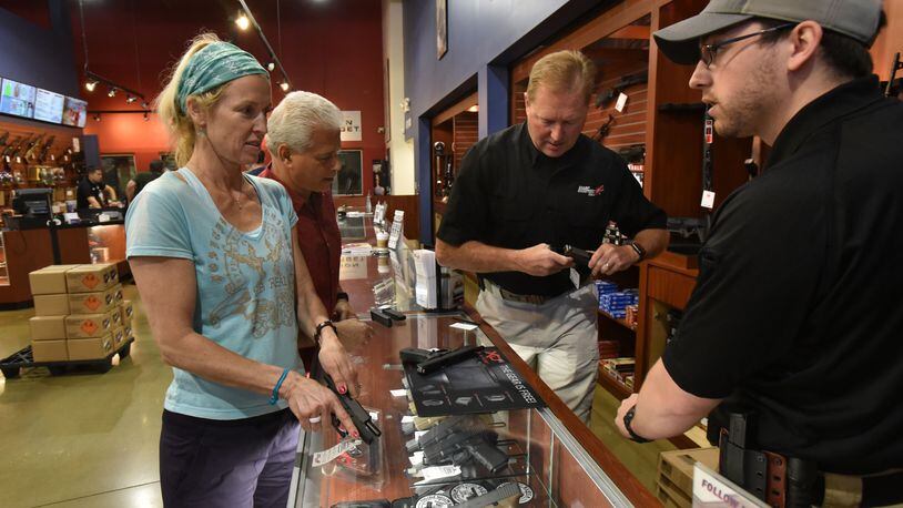 April 25, 2017 Roswell - Tom Deets (second from right), owner, and Garrett Polley (right) help customers Joe Banks and Julie Murray (left) at SharpShooters USA in Roswell on Tuesday, April 25, 2017. HYOSUB SHIN / HSHIN@AJC.COM