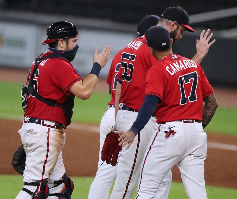 (From left) Braves catcher Travis D’Arnaud, pitcher Chris Martin and Johan Camargo celebrate closing out the New York Mets for an 11-10 victory Friday, July 31, 2020, at Truist Park in Atlanta. (Curtis Compton ccompton@ajc.com)