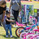 Porche Johnson helps her daughter Sanay Barry, 2,  pick out a new bike during the Sheriff's Office Saturday bike-a-thon in Atlanta on May 11, 2024.   (Steve Schaefer / AJC)