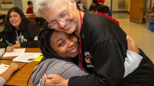 Osborne High School teacher Annette Hansard gets a hug from Ciara Witte during class on Friday, Sept. 20, 2019. She recently celebrated her 50th year of teaching social studies in that Cobb County school. She said she’s taught about 15,000 students over the last half century. PHIL SKINNER