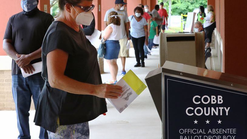 051820 Marietta: Nina Wilson drops off her absentee ballot while dozens of other voters line up to cast their votes in person on the first day of early voting at the Cobb County Board of Elections & Registration on Monday, May 18, 2020, in Marietta.   Curtis Compton ccompton@ajc.com