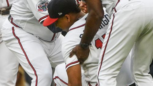 Braves rookie Johan Camargo is helped up by third base coach Ron Washington and bench coach Terry Pendleton after injuring his knee in a freak accident as he ran onto the field Aug. 8 before a game against the Phillies. (AP Photo/John Amis)