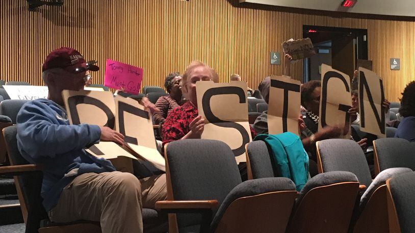 A group of protesters holds signs urging Gwinnett County Commissioner Tommy Hunter to resign during a Board of Commissioners meeting on Feb. 21.