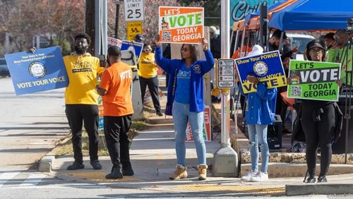 People wave signs to encourage early voting near the Metropolitan Library in Atlanta during early voting on Saturday, Nov.  26, 2022. (Photo: Steve Schaefer / steve.schaefer@ajc.com)