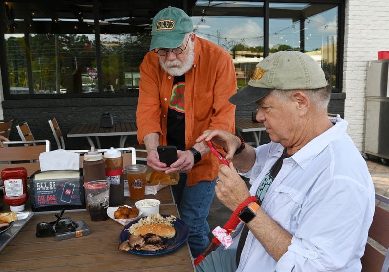 Roy Trimble (left) and Guy Tucker, photograph their barbecue plates at City Barbeque. Hyosub Shin / Hyosub.Shin@ajc.com)