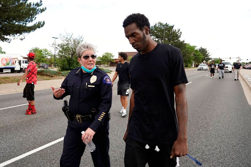 FILE - In this June 2, 2020, file photo, interim Aurora Police Chief Vanessa Wilson and Jay B. confer as protesters march north on South Chambers Road during a peaceful protest against police brutality following the death of George Floyd in Aurora, Colo. Multiple suburban Denver police officers have been placed on paid administrative leave amid an investigation into photos of them related to the case of a Black man who died last summer after he was stopped and restrained, police said Monday, June 29. Wilson said in a statement that the suspended officers were "depicted in photographs near the site where Elijah McClain died." But her statement did not provide more details about what the images show. (Philip B. Poston/The Aurora Sentinel via AP, File)