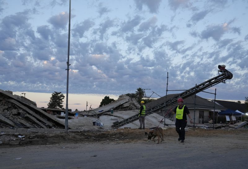 A rescue worker walks with a sniffer dog at the site of a building collapse in George, South Africa, Wednesday, May 8, 2024. Rescue operations continue for dozens of construction workers missing. (AP Photo/Nardus Engelbrecht)