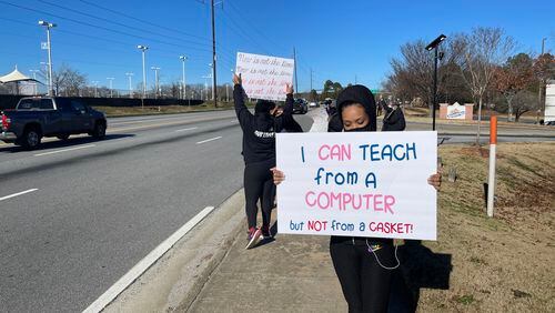 Community members in DeKalb held signs to protest against the reopening of DeKalb County schools.