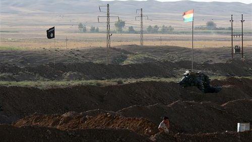 A Kurdish Peshmerga stands at the front line with the Islamic State group, their trademark black flags are seen and Kurdish flags in the background, in Kirkuk, 290 kilometers (180 miles) north of Baghdad, Iraq, Saturday, Sept. 27, 2014. The tense standoff frustrates many of the young soldiers, away from their families now for several months, even as other units make gains with the help of U.S. and French airstrikes. (AP Photo/Hadi Mizban) The battlefield in Iraq features the flags of two non-nations. The black Islamic State flag (left) and the Kurds (right). (AP Photo)