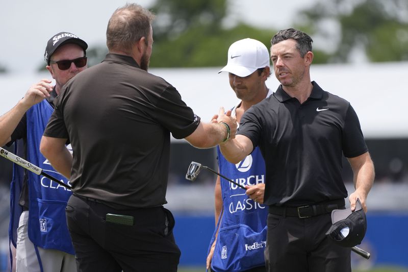 Rory McIlroy, of Northern Ireland, facing, congratulates teammate Shane Lowry, of Ireland, after finishing the day on the ninth green during the second round of the PGA Zurich Classic golf tournament at TPC Louisiana in Avondale, La., Friday, April 26, 2024. (AP Photo/Gerald Herbert)