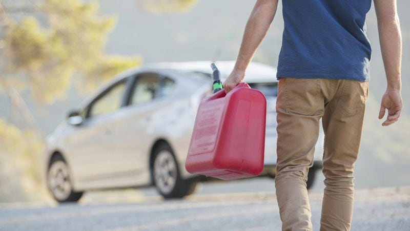 File photo - Man carrying gas can to car at roadside