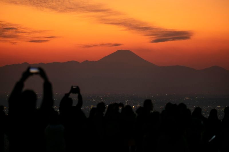 FILE- Visitors take pictures of Mount Fuji from Shibuya Sky observation deck Monday, Jan. 20, 2020, in the Shibuya district of Tokyo. (AP Photo/Jae C. Hong, File)