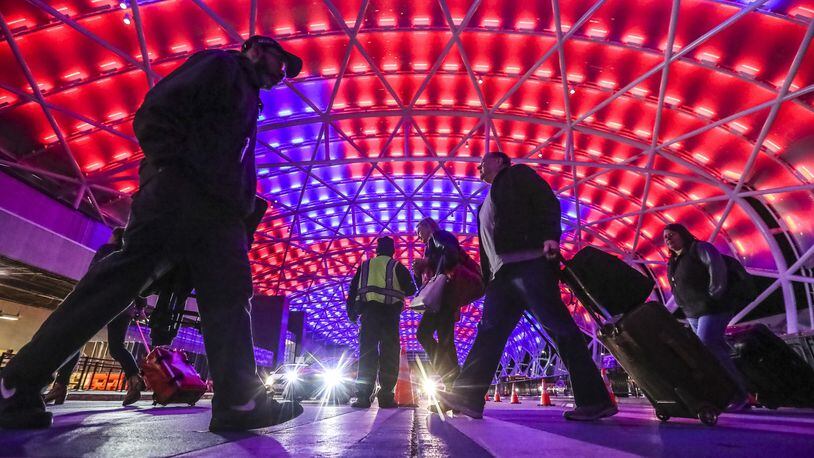Under Super Bowl colors passengers travel under the illuminated canopy on the North Terminal at Hartsfield-Jackson International Airport that was bustling with passengers arriving for the Super Bowl Friday, Feb. 1, 2019 and airport officials are ramping up operations for even heavier traffic to come. JOHN SPINK/JSPINK@AJC.COM