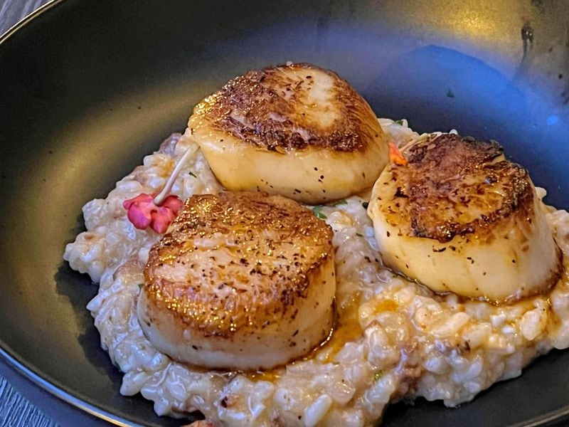 Tender, sweet scallops at El Valle are bolstered by creamy risotto infused with chorizo. Henri Hollis/henri.hollis@ajc.com