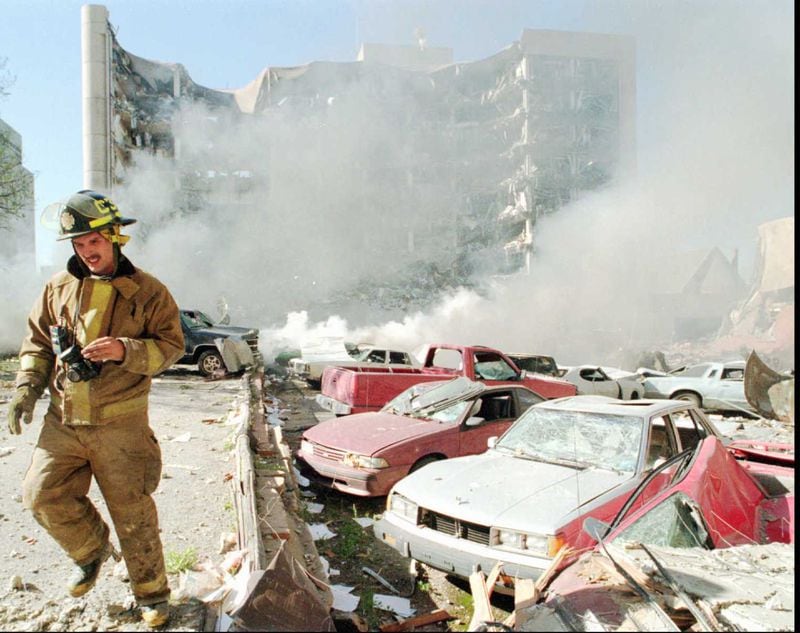 An Oklahoma City firefighter walks near explosion-damaged cars on the north side of the Alfred Murrah Federal Building in Oklahoma City after a bomb blast on April 19, 1995.