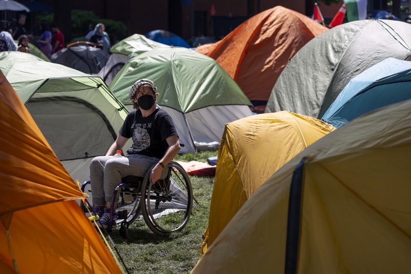 A person who declined to give their name maneuvers among tents at an encampment by students protesting against the Israel-Hamas war at George Washington University on Monday, April 29, 2024, in Washington. (AP Photo/Mark Schiefelbein)