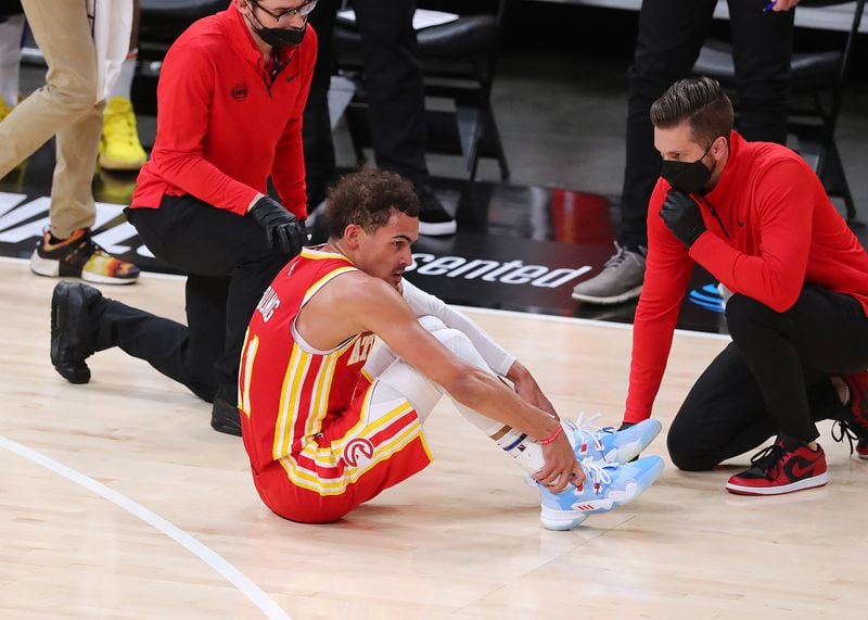 Hawks guard Trae Young is tended to on the floor with a possible ankle injury during the third quarter of Game 3 of the Eastern Conference finals against the Milwaukee Bucks Sunday, June 27, 2021, in Atlanta. (Curtis Compton / Curtis.Compton@ajc.com)