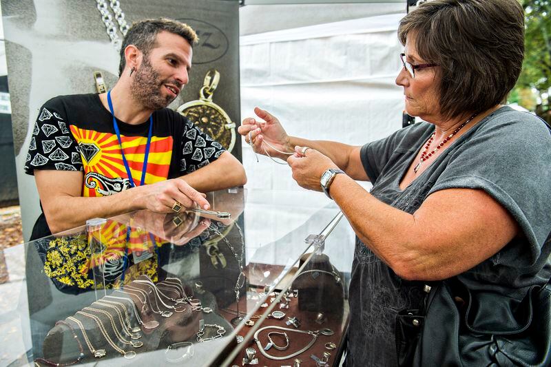Hanan Ingel (left) talks with Terri Morgan as she tries to decide which necklace to purchase during the Chastain Park Arts Festival on Saturday, November 7, 2015. Rainy weather would not stop the two day festival featuring 185 artists. JONATHAN PHILLIPS / SPECIAL