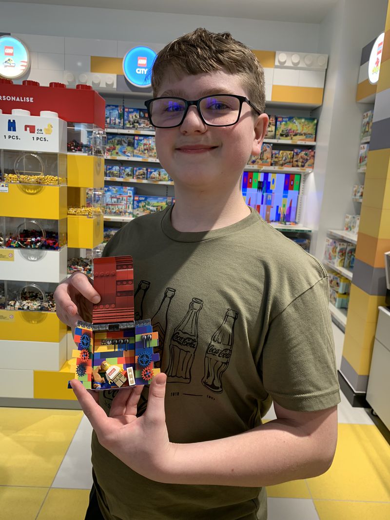 Connor Flood of Clinton, Michigan, shows off his personalized Lego mini-figure he created in the Lego Discovery Center gift shop on re-opening day March 31, 2023. RODNEY HO/rho@ajc.com