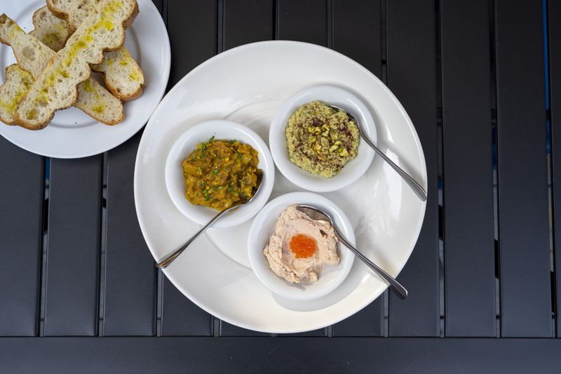 The trio of dips includes, clockwise from left, grilled eggplant mirza ghasemi dip, pea and pistachio hummus and salmon tarama, the star of the group.  Courtesy of Dara Paryas