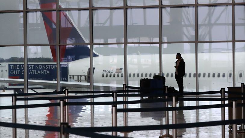 A Delta plane sits at the International Terminal at Hartsfield Jackson International Airport with a solitary traveler waiting for a flight amid new European travel restrictions on Monday, March 16, 2020, in Atlanta. International and domestic air travel have been hammered by the coronavirus. (Curtis Compton/Atlanta Journal-Constitution/TNS)