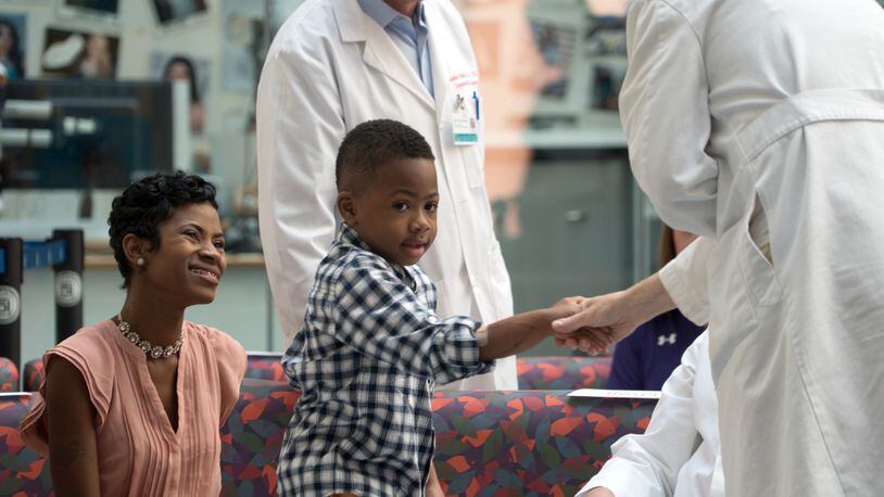 Zion Harvey, center, who received a double hand transplant in July 2015, shakes hands with a health care worker as his mother Pattie Ray, left, smiles during a news conference Aug. 23, 2016 at The Children's Hospital of Philadelphia in Philadelphia.