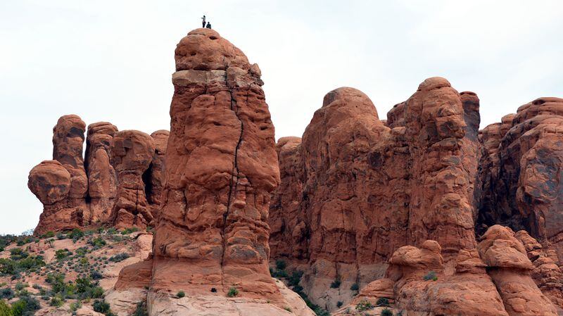 A pair of climbers in Arches National Park stands atop a chimney after scaling the beast. (David Whiting/Orange County Register/TNS)
