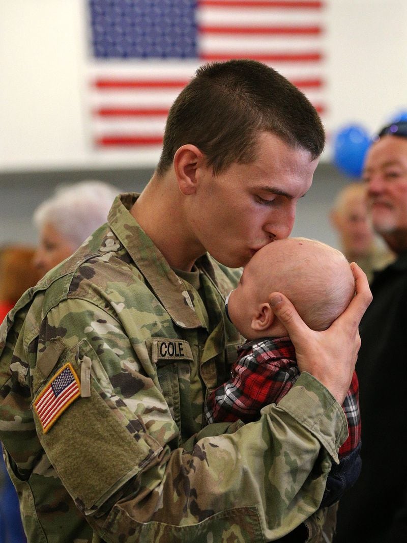 Spc. Devin Cole, a Georgia National Guardsman, gives his 2-month-old son, Dylan, a kiss goodbye before he boards a bus at the armory in Dalton. His unit is heading to Afghanistan for nine months. Curtis Compton/ccompton@ajc.com