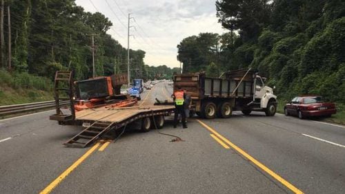 After an accident, a bulldozer fell off a truck, blocking lanes of traffic on a road in north Fulton County on Thursday.