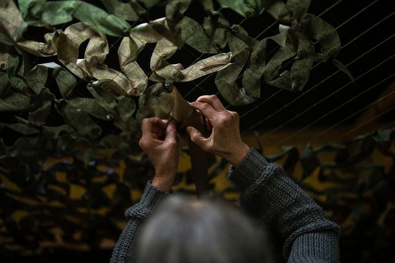 A volunteer makes a camouflage net at a facility producing material for Ukrainian soldiers in Kyiv, Ukraine, Monday, April 22, 2024. A newly approved package of $61 billion in U.S. aid may prevent Ukraine from losing its war against Russia. But winning it will be a long slog. (AP Photo/Francisco Seco)