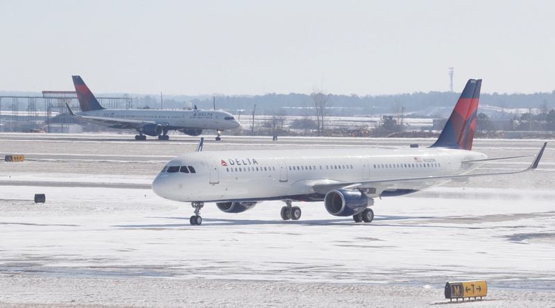 Delta plane sits on tarmac with snow at Hartsfield-Jackson Airport.