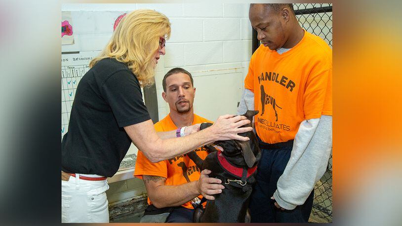 (left to right) Susan Jacobs-Meadows takes a look at Omega with handlers Jeff M & Desmon C at the Fulton County Jail as part of Canine Cellmates founded by Jacobs-Meadows 6.5 years ago. The program pairs dogs from Fulton County Animal Services that live & train with inmates at the Jail annex in Atlanta. The dogs go through a series of temperament tests to make sure that are a good fit for the program. Currently 11 inmates are training 6 dogs working on skills they will display during their graduation ceremony. Four of the six dogs have already been adopted & those adoptive parents get the opportunity to attend graduation to meet the inmates that trained their dog. (Photo by Phil Skinner)