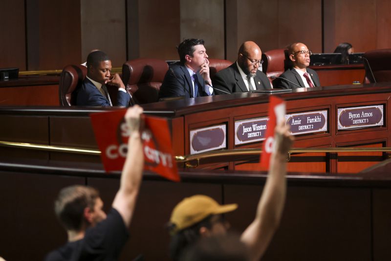 Council members listen to a member of the public speak as protestors hold signs ahead of the final vote to approve legislation to fund the training center on Monday, June 5, 2023, in Atlanta. (Jason Getz / Jason.Getz@ajc.com)