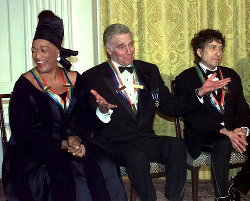 Kennedy Center Honoree Charlton Heston, center, acknowledges the applause of the audience flanked by singer/songwriter Bob Dylan at right, and soprano Jessye Norman at a gala reception in the East Room of the White House hosted by President and Mrs. Clinton Sunday evening, Dec. 7, 1997.