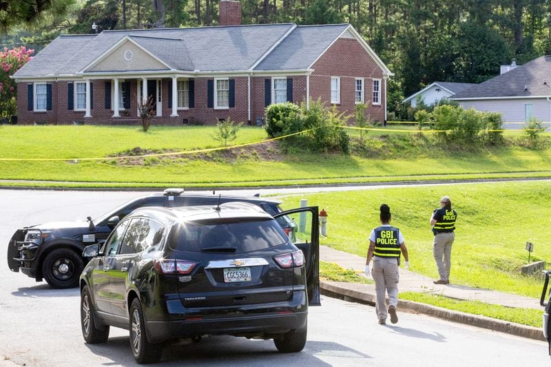 Members of the GBI look over and take pictures of homes that are surrounded by crime scene tapes after a mass shooting in Hampton on Saturday.