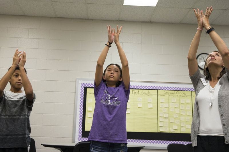 Berkeley Lake Elementary School counselor Laura Penland (right) participates in a deep breathing exercise with fifth-graders Zihan Wang (center) and Giovanni Hernandez (left) at the school. ALYSSA POINTER / ALYSSA.POINTER@AJC.COM