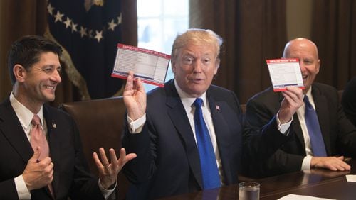 President Donald Trump on Thursday displays examples of what a “postcard” tax return might look like under the Republican tax plan. He’s flanked by U.S. House Ways and Means Committee Chairman Kevin Brady, R-Texas, right, and House Speaker Paul Ryan, R-Wis., inside the Cabinet Room at the White House. Republican lawmakers unveiled a sweeping rewrite of the tax code Thursday, outlining a $1.51 trillion plan that would cut corporate taxes to 20 percent while delivering more modest savings for middle-class families. (Tom Brenner/The New York Times)