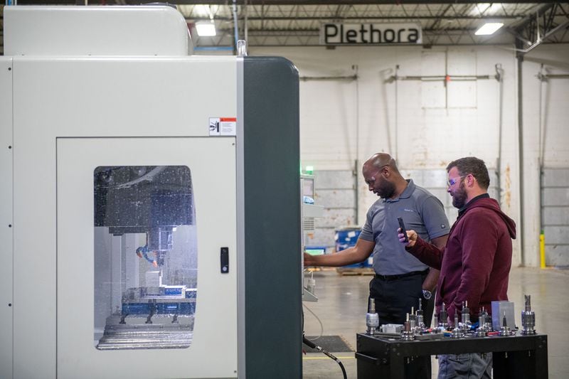 (L-R) Nathan Peynado a field engineer with Texmac, and Bryan Mackey, a maintenance foreman, test a new machine at Plethora, a company that makes custom prototypes, in Marietta in December. Plethora serves customers across the United States in a variety of industries, including robotics, automotive, aerospace and consumer packaged goods. PHOTO BY ELISSA BENZIE