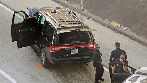Los Angeles police officers stand after a pursuit of a stolen hearse with a casket and body inside in South Los Angeles on Thursday. The hearse was stolen from outside a Greek Orthodox church in East Pasadena on Wednesday night. The Los Angeles County Sheriff's Department said one person is in custody.