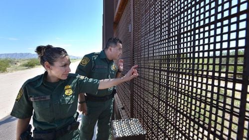 Sunland Park, N.M.- U.S. Border Patrol agents Vennesa Martinez (left) and George Gomez peer through an existing border fence across from the Mexican town of Anapra. Five Georgia companies have signaled interest in President Donald Trump’s proposal to build a new wall on the southwest border. Sept. 26, 2013. HYOSUB SHIN / HSHIN@AJC.COM