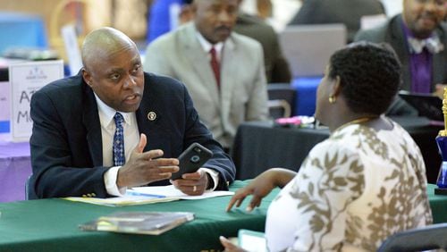Rodney Swanson, principal of Arabia Mountain High School, talks with a prospective candidate as teachers interview during a job fair earlier this month. KENT D. JOHNSON / AJC