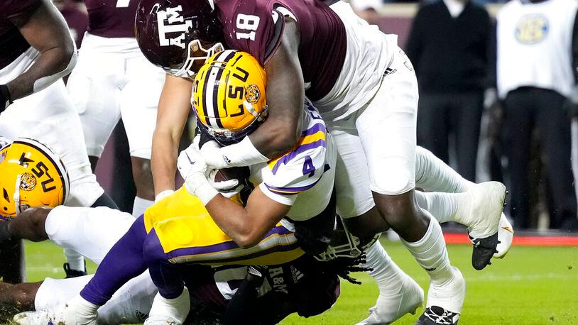 LSU running back John Emery Jr. (4) drags Texas A&M defensive lineman LT Overton (18) across the goal line for a touchdown during the first half of an NCAA college football game Saturday, Nov. 26, 2022, in College Station, Texas. (AP Photo/Sam Craft)