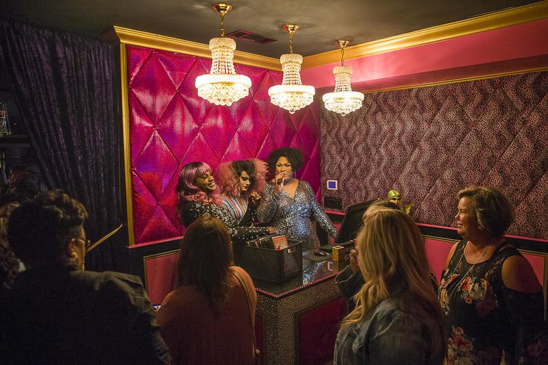 Drag queens Shavonna Brooks (background, from right), Gigi Diamond (background, center) and Lala Ri (background, left), welcome guests in the lobby at Lips in Atlanta. Lips owner Mark “Yvonne Lame” Zschiesche says that television shows like “RuPaul’s Drag Race” have catapulted drag to another level.