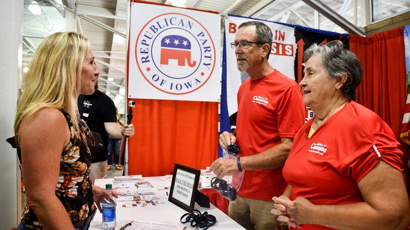 Rep. Marjorie Taylor Greene speaks with members of the Republican Party of Iowa at their Iowa State Fair Varied Industries booth. Daniel Freeman (middle) told the congresswoman he was excited to see her coming to Iowa and she had "a lot of" support in the state. (Anjali Huynh / Anjali.Huynh@ajc.com)