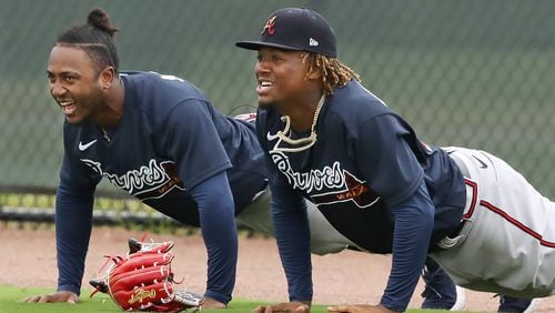 Ozzie Albies (left) and Ronald Acuna hit the ground for pushups in the outfield after missing fly balls during batting practice Feb. 21, 2020, at spring training workouts in North Port, Fla.