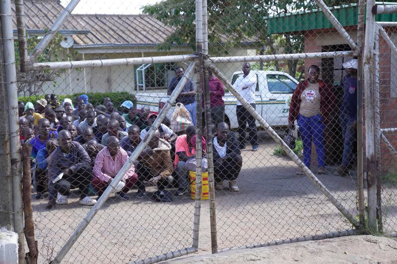 Prisoners kneel at the entrance of Chikurubi Maximum prison before their release on the outskirts of the capital Harare, Thursday, April 18, 2024. Zimbabwe President Emmerson Mnangagwa has granted amnesty to more than 4,000 prisoners in an independence day amnesty. The amnesty coincided with the country's 44th anniversary of independence from white minority rule on Thursday and included some prisoners who were on death row. (AP Photo/Tsvangirayi Mukwazhi)
